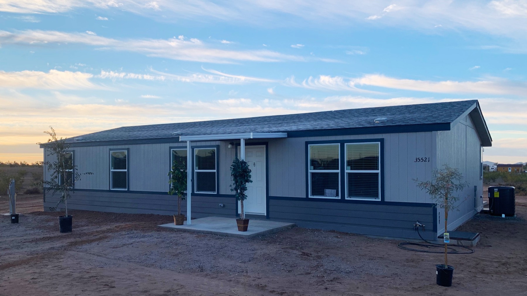 A new Record home at sunset in the West Valley, blue trim, porch light on