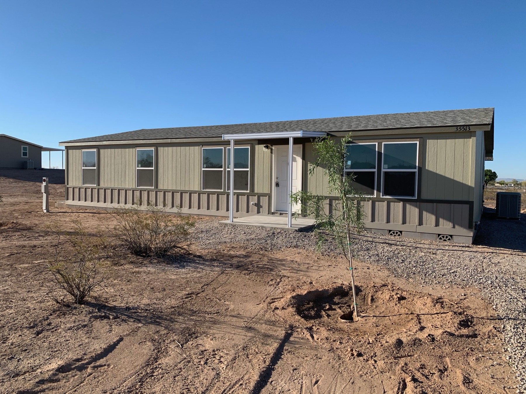 Tan home with a covered front porch on a graded lot